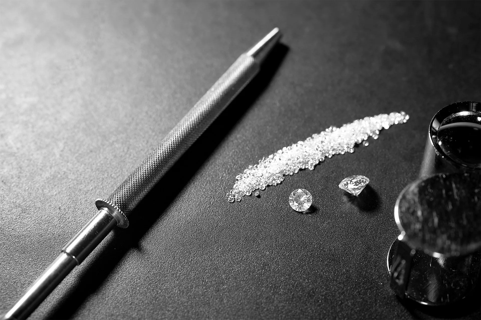 Diamanti sciolti sul banco di lavoro accanto alla lima e alle lenti