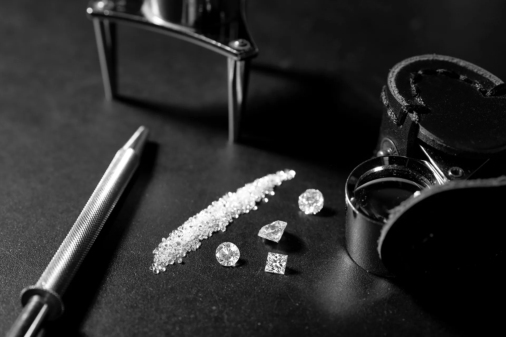 Diamanti di tagli diversi accanto alla lente e alle pinzette